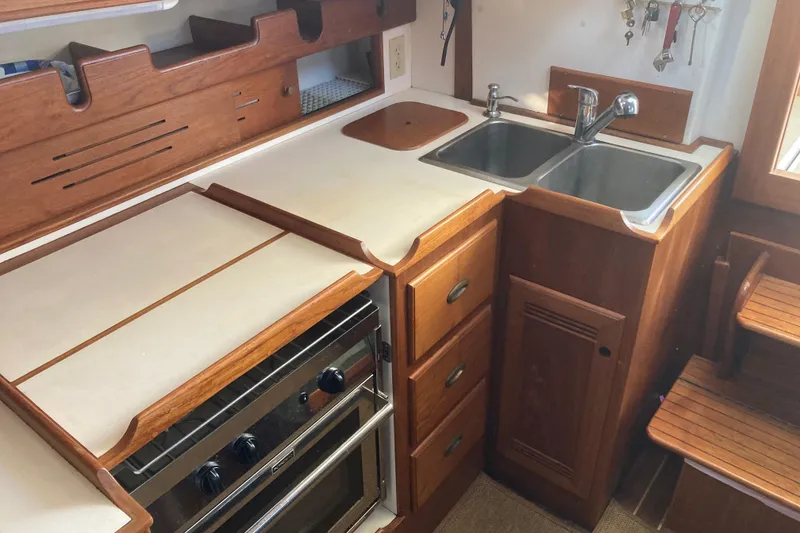 Slide: The Image of 1989 Cape Dory 300 Motorsailer kitchen with wooden cabinetry, dual sink, and stove. - 10