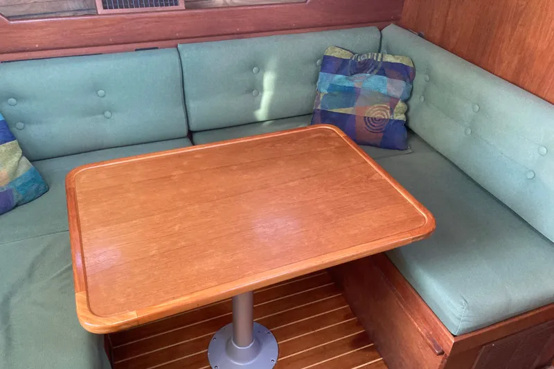 Slide: The Image of Interior of 1989 Cape Dory 300 Motorsailer with wooden table and green cushioned seating. - 16
