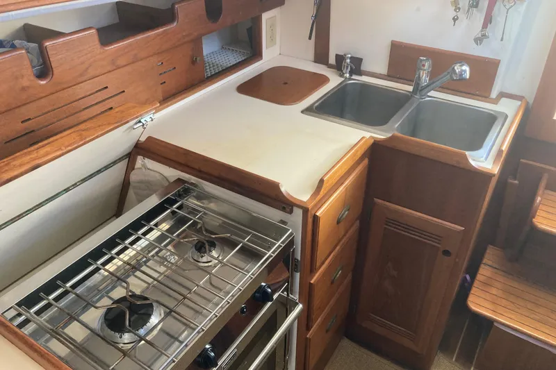 Slide: The Image of 1989 Cape Dory 300 Motorsailer kitchen with stove, sink, and wooden cabinetry. - 9