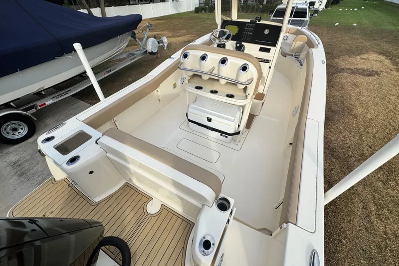 Slide: The Image of 2023 Scout 240 XSF boat interior with seating and control panel, docked outdoors. - 10
