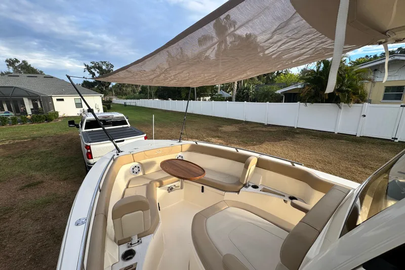 Slide: The Image of 2023 Scout 240 XSF boat with sunshade, parked in a residential yard. - 20