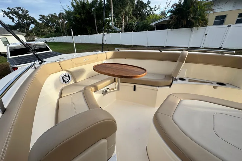 Slide: The Image of 2023 Scout 240 XSF boat interior with beige seating and wooden table. - 21