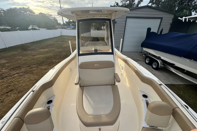 Slide: The Image of 2023 Scout 240 XSF boat with beige seating, parked outdoors near a garage. - 24