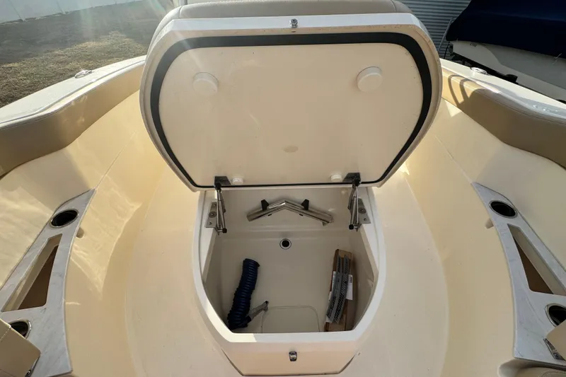 Slide: The Image of 2023 Scout 240 XSF boat storage compartment with open lid and accessories inside. - 25