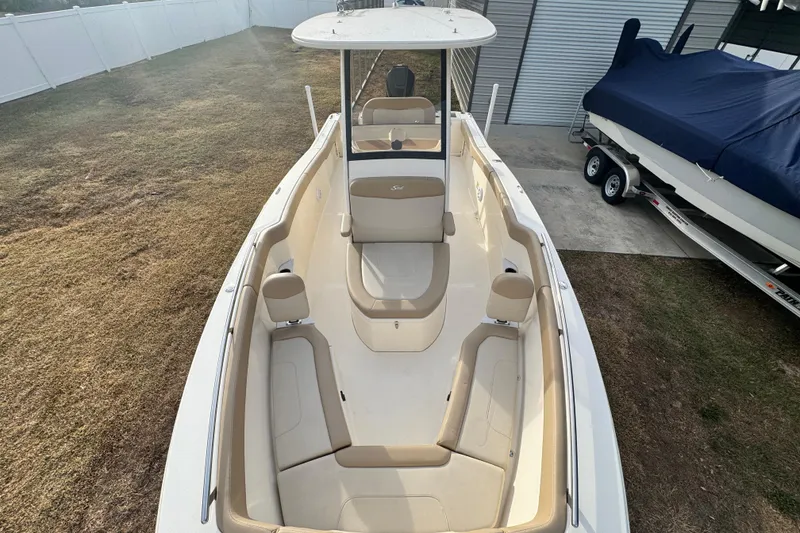 Slide: The Image of 2023 Scout 240 XSF boat with beige seating, parked outdoors near a covered boat. - 26