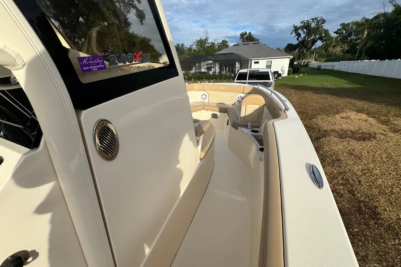 Slide: The Image of 2023 Scout 240 XSF boat with beige interior, parked in a grassy yard. - 30