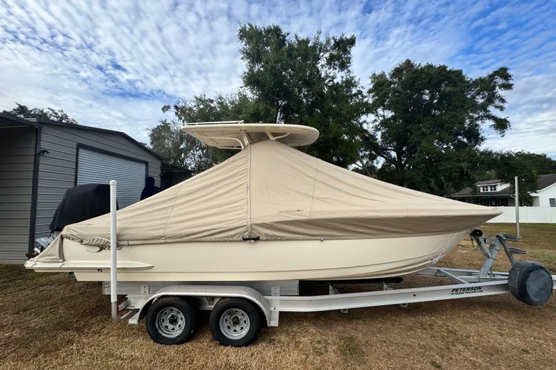 Slide: The Image of 2023 Scout 240 XSF boat covered on trailer, parked outdoors under cloudy sky. - 36