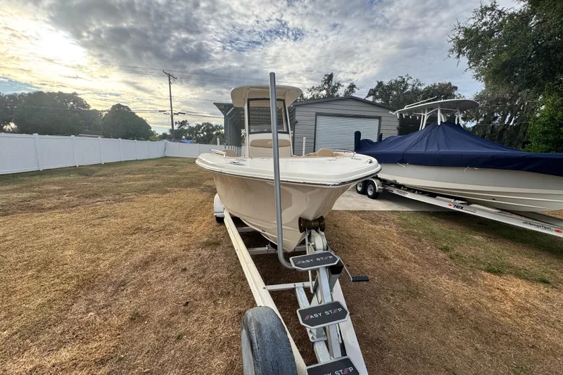 Slide: The Image of 2023 Scout 240 XSF boat on trailer, parked outdoors under cloudy sky. - 4