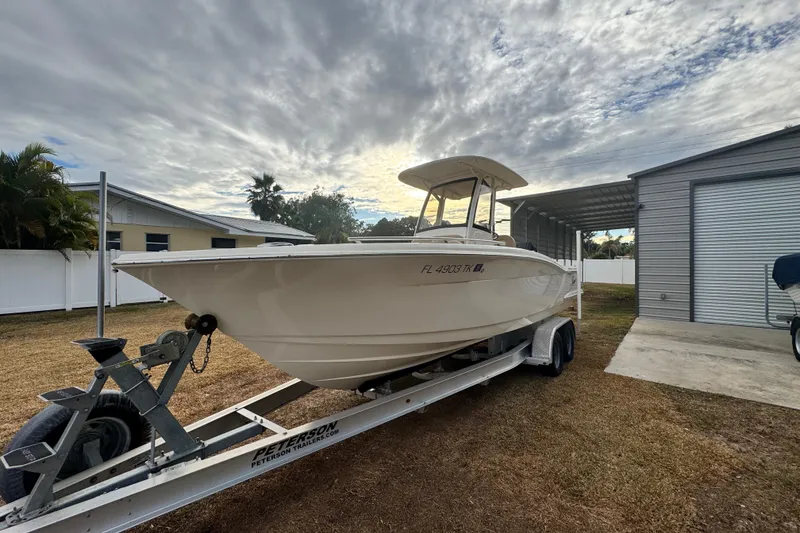 Slide: The Image of 2023 Scout 240 XSF boat on trailer, parked outdoors under cloudy sky. - 5