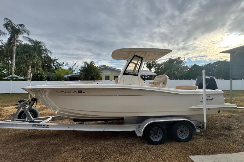 Slide: The Image of 2023 Scout 240 XSF boat on trailer, parked outdoors under cloudy sky. - 6