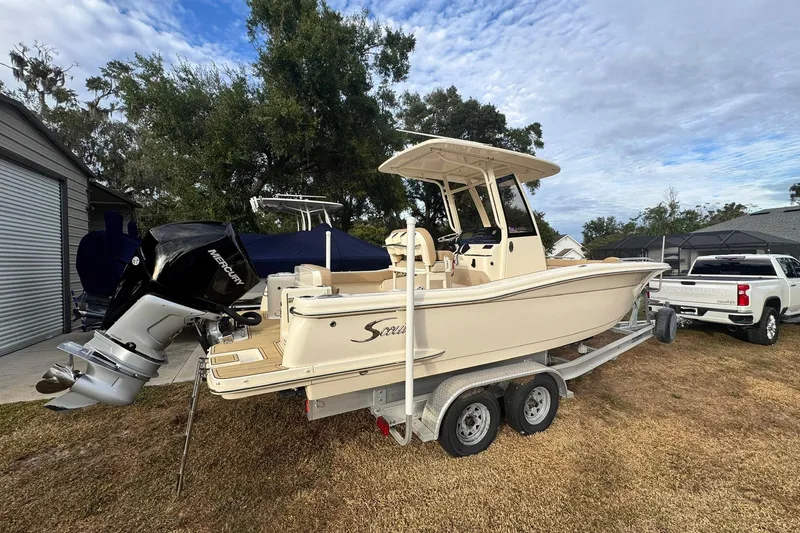 Slide: The Image of 2023 Scout 240 XSF boat on trailer with Mercury outboard motor, parked outdoors. - 9