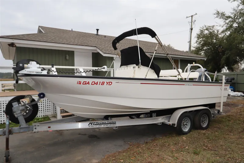 The Image of 2013 Boston Whaler 210 Montauk boat on trailer, parked near a house. - 0