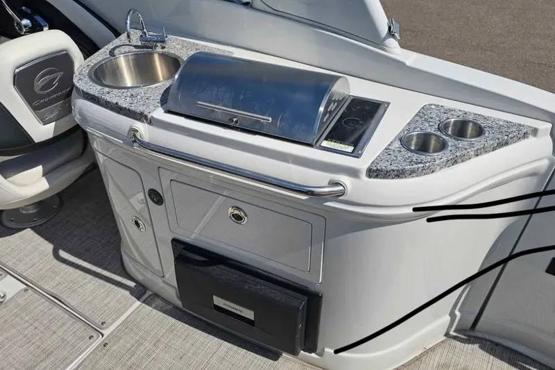 Slide: The Image of 2024 Crownline Eclipse E290 XS boat kitchenette with sink, grill, and cup holders. - 7