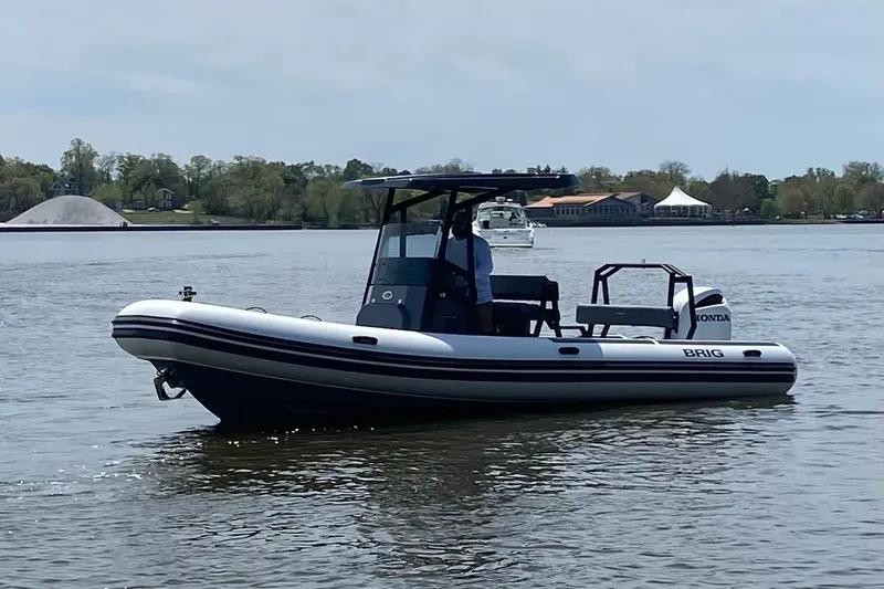 The Image of 2026 Brig Navigator 24 boat on calm water, featuring a sleek design and Honda engine. - 1