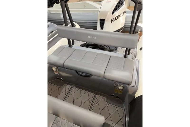 Slide: The Image of 2026 Brig Navigator 24 boat interior with Honda engine, featuring gray seating and flooring. - 14