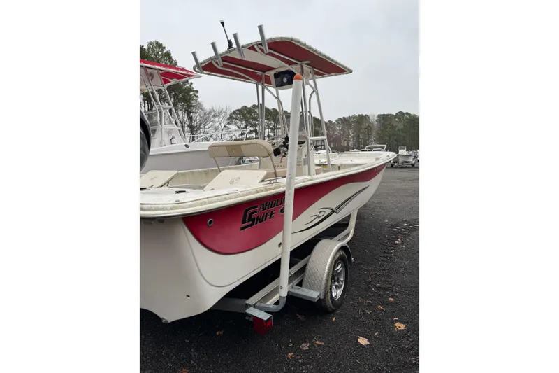 Slide: The Image of 2017 Carolina Skiff 218 DLV boat on trailer, red and white design, parked outdoors. - 2