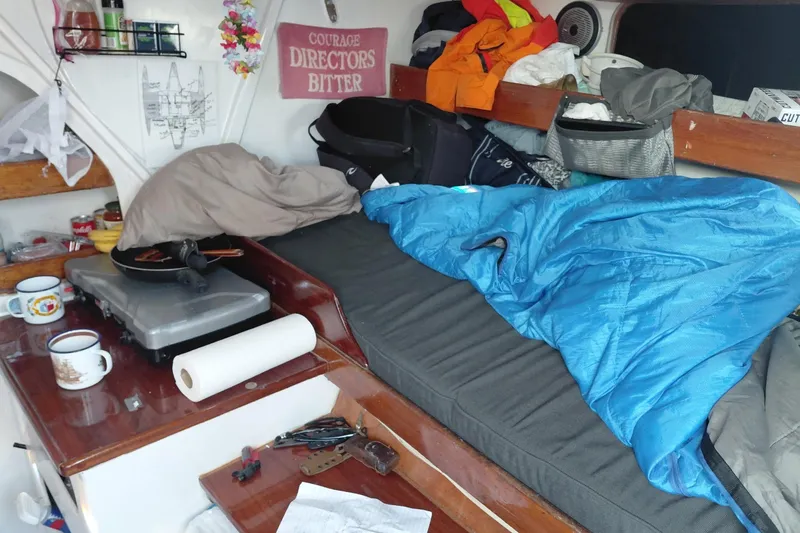 Slide: The Image of Cozy cabin interior of a 1979 Newick Native boat with bedding and kitchen essentials. - 12