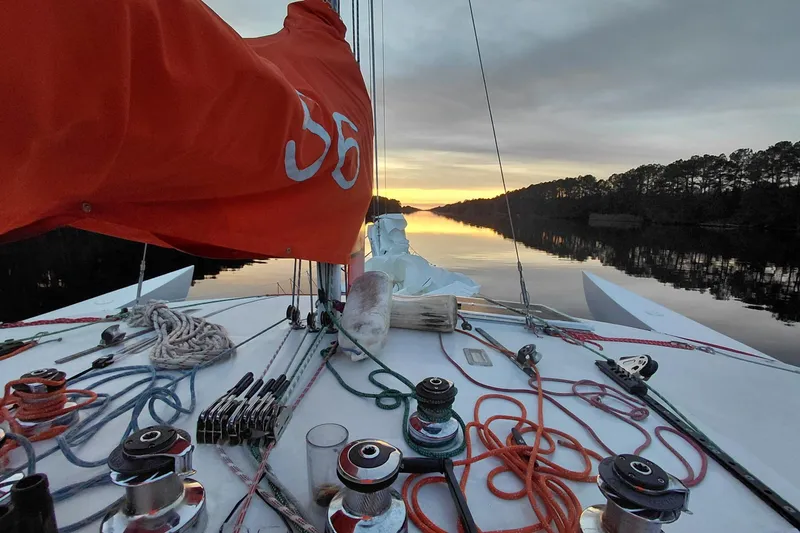 Slide: The Image of Sailboat deck at sunset, Newick Native 1979, with vibrant orange sail and ropes. - 5