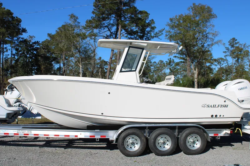 The Image of 2026 Sailfish 252 CC boat on trailer, side view, outdoors with trees in background. - 0