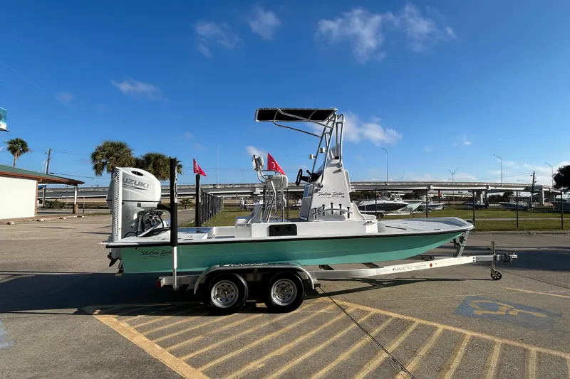 Slide: The Image of 2026 Shallow Stalker CAT 211 PRO boat on trailer, parked outdoors under clear blue sky. - 4