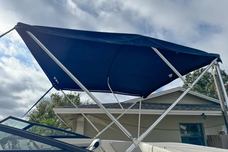 Slide: The Image of 2021 Sea Ray SPX 190 Outboard with blue bimini top under cloudy sky. - 10