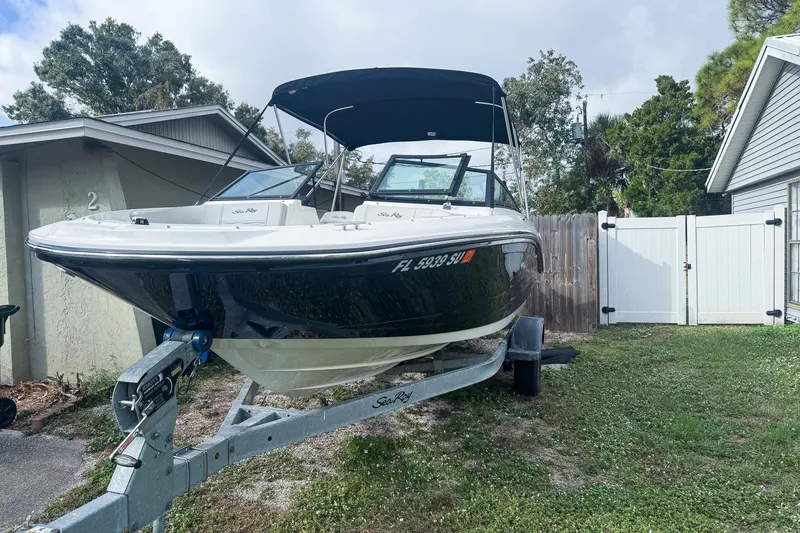 Slide: The Image of 2021 Sea Ray SPX 190 Outboard boat on trailer, parked beside a house. - 2