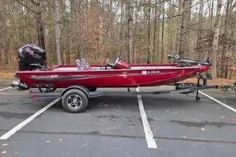 The Image of 2023 Ranger RT188C boat in red, parked in a wooded area. - 0
