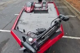 Slide: The Image of 2023 Ranger RT188C fishing boat, red, parked in a lot, featuring spacious deck and seating. - 2