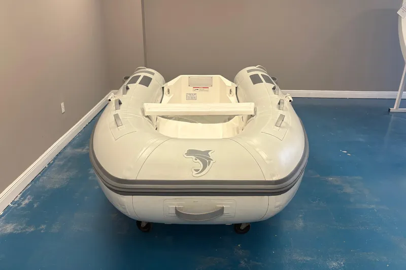 Slide: The Image of 2025 Caribe L-8 inflatable boat displayed indoors with motor and plants. - 4