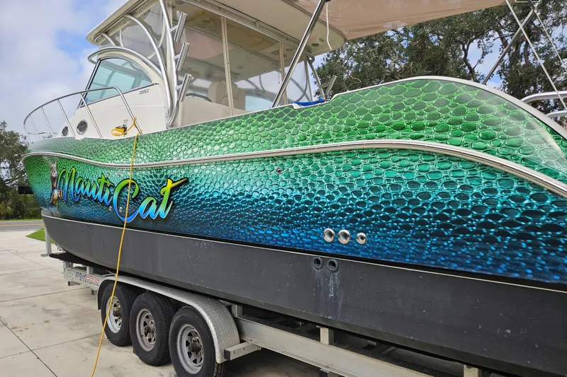 Slide: The Image of 2014 World Cat 320 EC boat with vibrant green and blue scale design on trailer. - 3