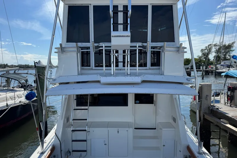 Slide: The Image of 1995 Viking 58 Convertible yacht docked at marina, rear view with ladder and windows. - 10