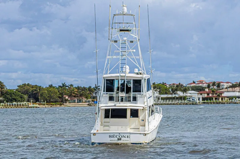 Slide: The Image of 1995 Viking 58 Convertible yacht cruising near coastal homes under cloudy skies. - 3
