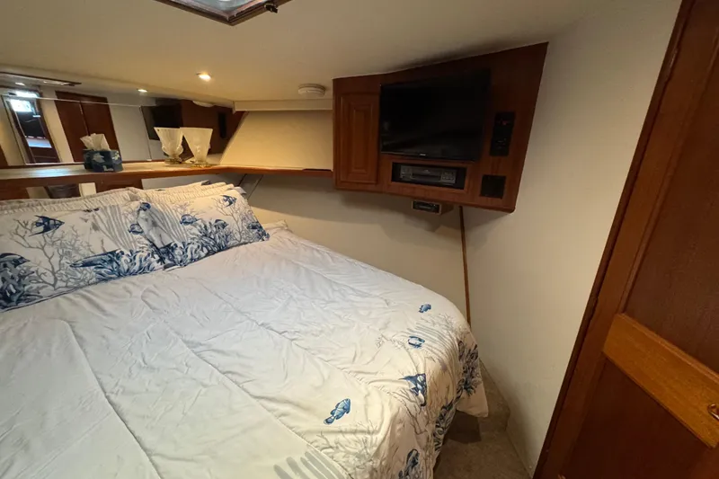 Slide: The Image of Cozy bedroom in 1995 Viking 58 Convertible yacht with nautical-themed bedding and built-in TV. - 30