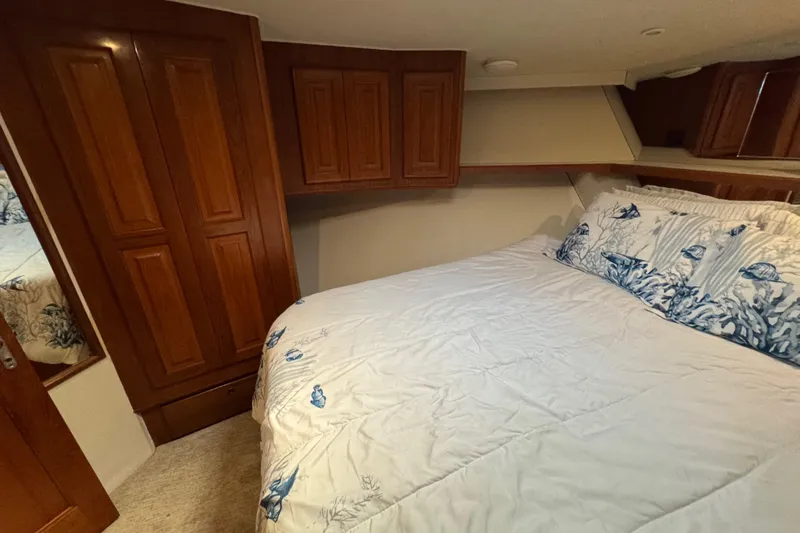 Slide: The Image of Cozy bedroom in 1995 Viking 58 Convertible yacht with wooden cabinets and nautical-themed bedding. - 31