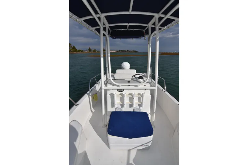Slide: The Image of 2015 Boston Whaler 190 Montauk boat interior with blue seat and canopy on calm water. - 13