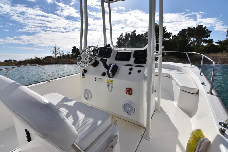 Slide: The Image of 2015 Boston Whaler 190 Montauk boat interior with steering console and seating, under a clear sky. - 8