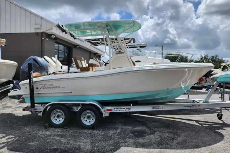 Slide: The Image of 2026 Pioneer 202 Islander boat on trailer, parked outdoors under cloudy sky. - 13