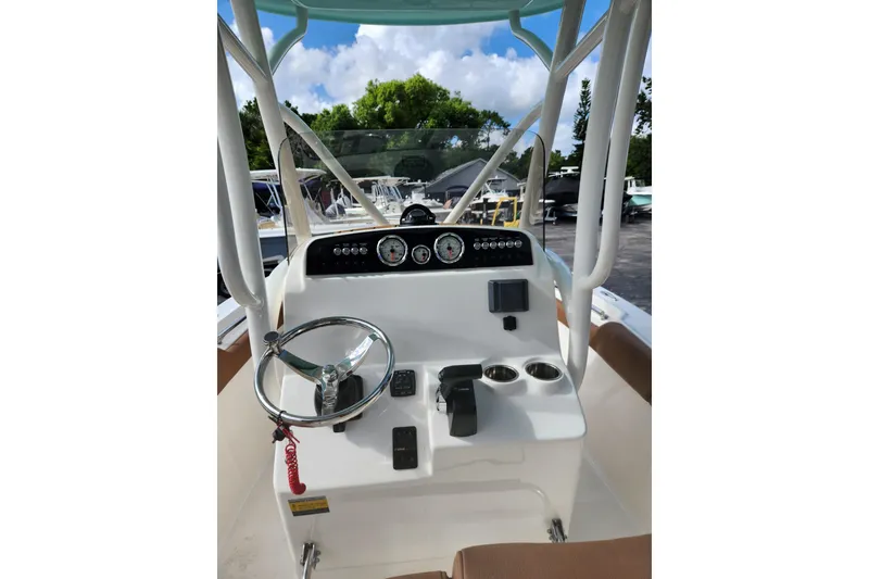 Slide: The Image of 2026 Pioneer 202 Islander boat dashboard with steering wheel and controls, under a clear blue sky. - 6