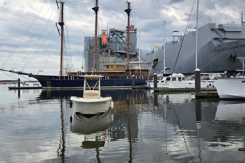 Slide: The Image of 2023 Scout 215 XSF boat docked in a marina with large ships in the background. - 3