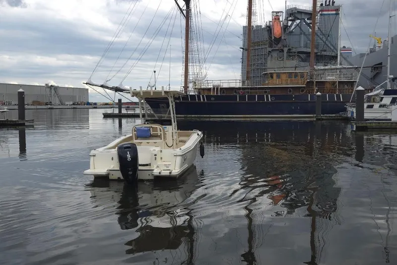 Slide: The Image of 2023 Scout 215 XSF boat docked near a large ship in a marina. - 4