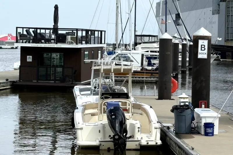 Slide: The Image of 2023 Scout 215 XSF boat docked at marina with floating house nearby. - 5