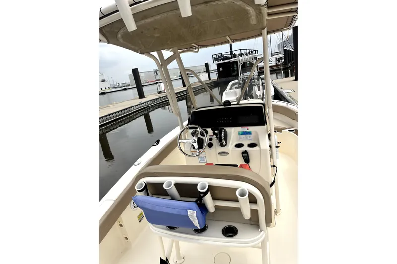 Slide: The Image of 2023 Scout 215 XSF boat interior with steering console and rod holders at dock. - 7