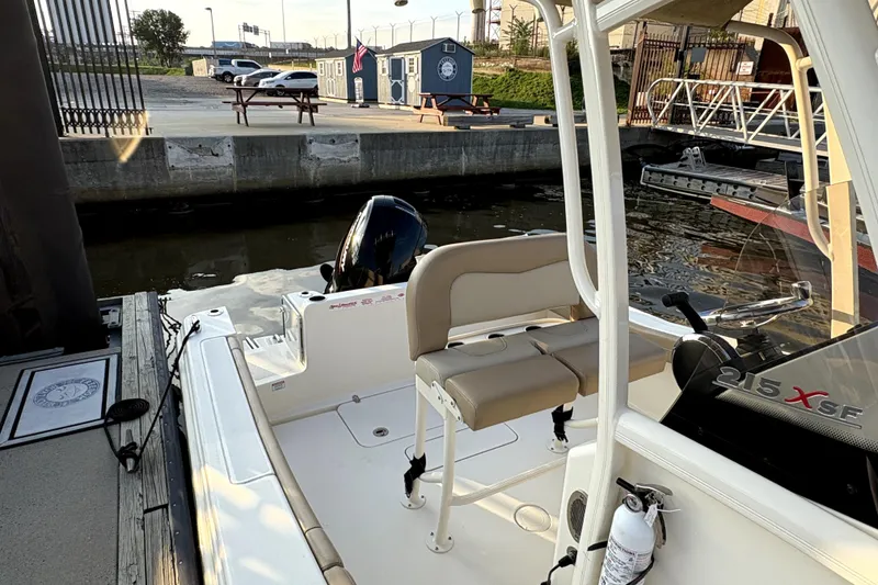 Slide: The Image of 2023 Scout 215 XSF boat docked, featuring seating and outboard motor. - 8