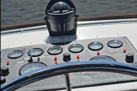 Slide: The Image of 1988 Canoe Cove Tri-Cabin dashboard with gauges and compass, overlooking water. - 12