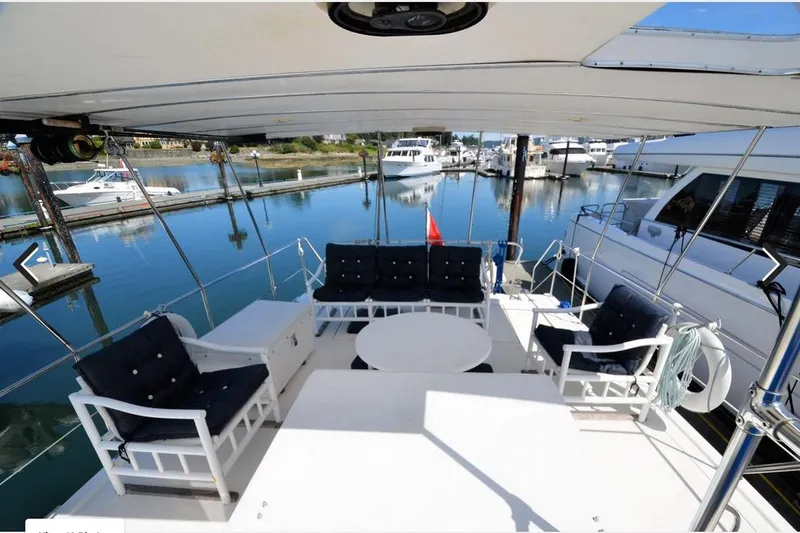 Slide: The Image of 1988 Canoe Cove Tri-Cabin yacht deck with seating, table, and marina view. - 14