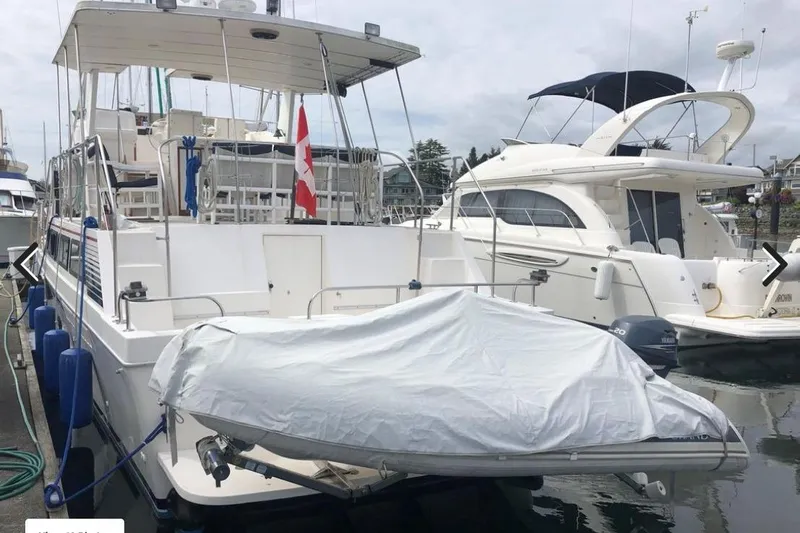 Slide: The Image of 1988 Canoe Cove Tri-Cabin yacht docked with covered dinghy and Canadian flag. - 16