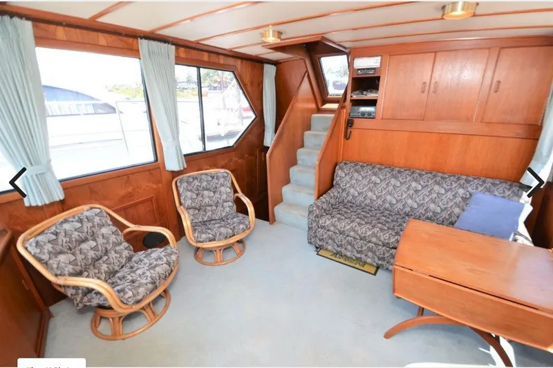 Slide: The Image of 1988 Canoe Cove Tri-Cabin interior with cozy seating, wooden accents, and large windows. - 2