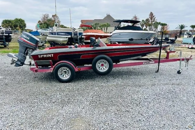 Slide: The Image of 1997 Sprint 267 boat on trailer with Yamaha outboard motor, parked on gravel lot. - 1