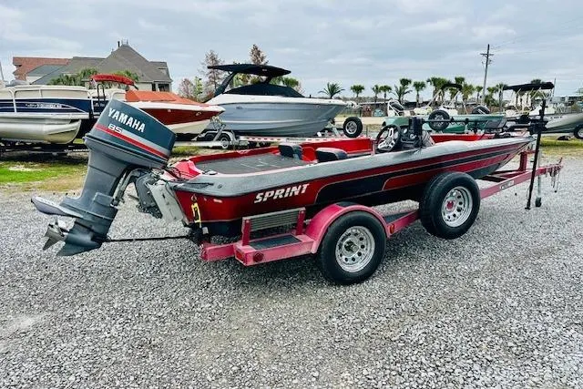 Slide: The Image of 1997 Sprint 267 boat with Yamaha engine on a trailer, parked on gravel. - 2