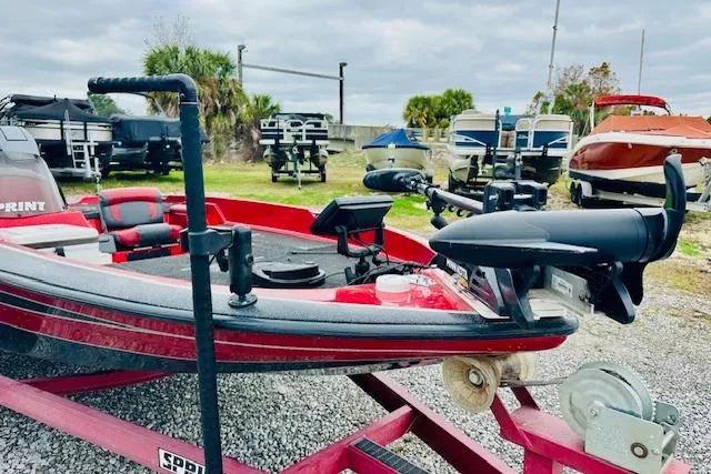 Slide: The Image of 1997 Sprint 267 boat on trailer, surrounded by other boats, under cloudy sky. - 7